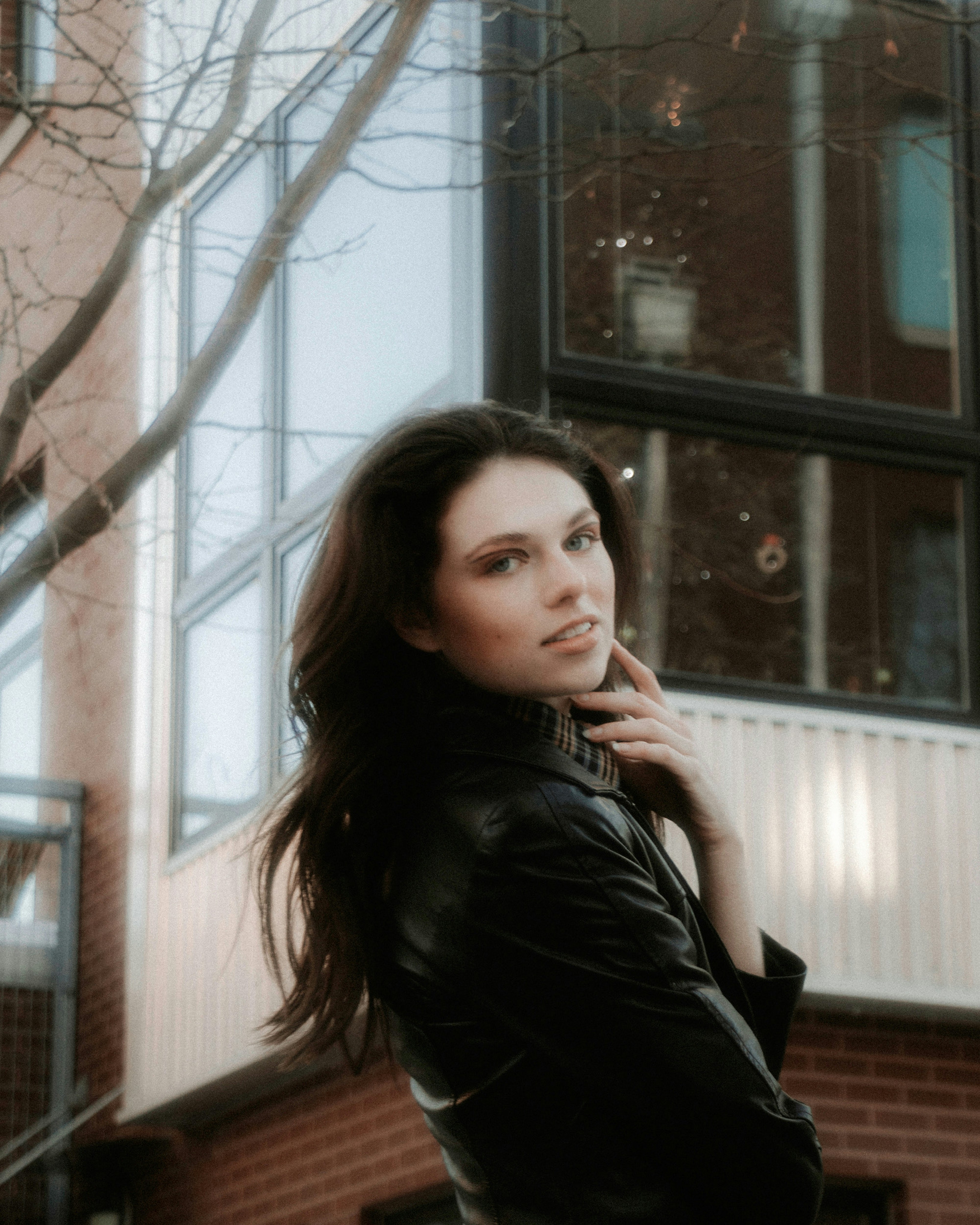 woman in black leather jacket standing near bare tree during daytime